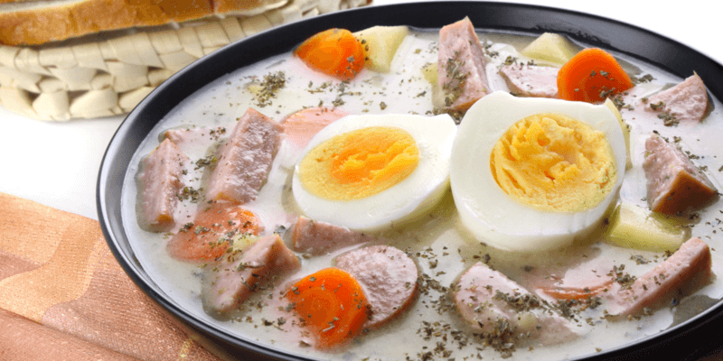 W głębokim talerzu podano biały barszcz z białą kiełbasą, marchewką, ziemniakami i jajkiem.