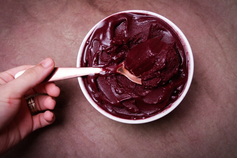 Osoba nabiera na dużą łyżkę pysznych, owocowych lodów domowej produkcji prosto z miski.