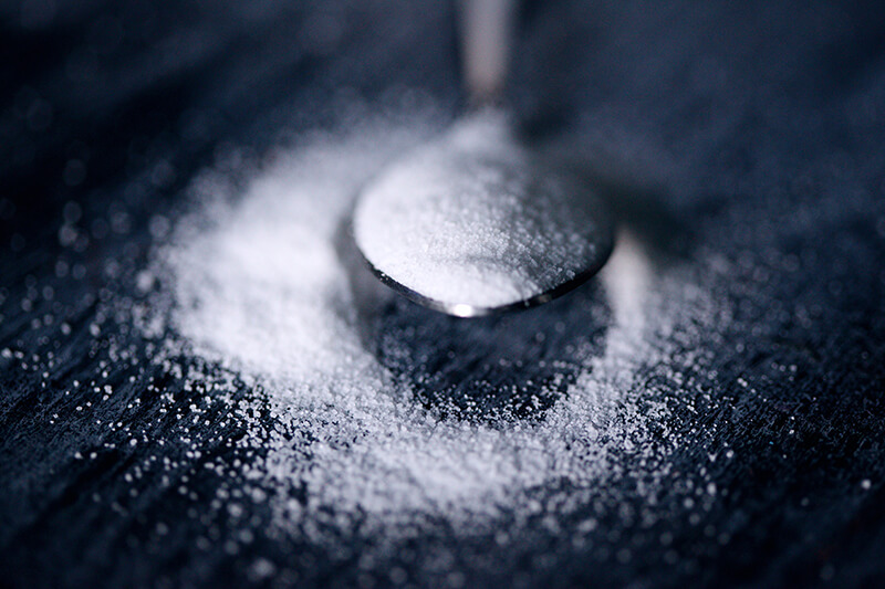 Na łyżeczkę wysypano słodzik i erytrytol rozsypał się również dookoła.