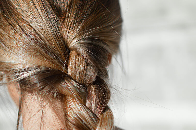 Kobieta ma słomkowe blond włosy zaplecione w piękny, gruby warkocz.