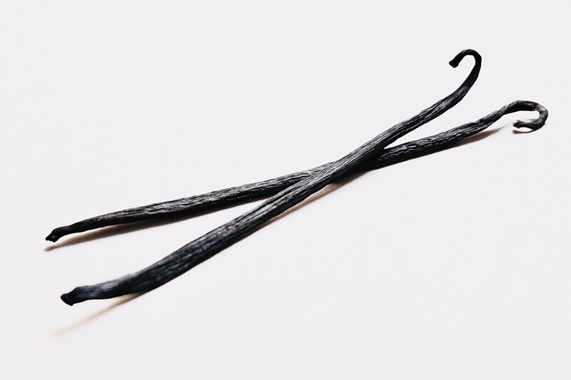 Na stole leżą dwie laski prawdziwej wanilii bourbon z Madagaskaru o najintensywniejszym aromacie.