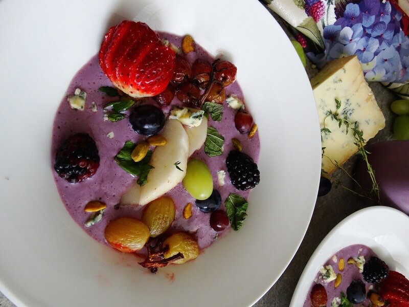 Obok siebie leżą dwa talerze pełne owocowe zupy i przyozdobione różnymi owocami lata.